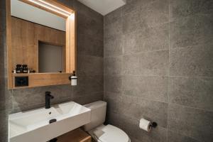 bagno con lavandino, servizi igienici e specchio di Hotel Brocco & Posta a San Bernardino