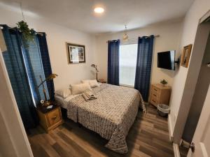 a bedroom with a bed with blue curtains and a tv at Walk to Hard Rock ~ Amazing 5 Star Home Away From Home! in Miami Gardens