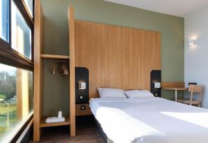 Un dormitorio con una gran cama blanca y una ventana en B&B HOTEL Grenoble Centre Verlaine, en Grenoble