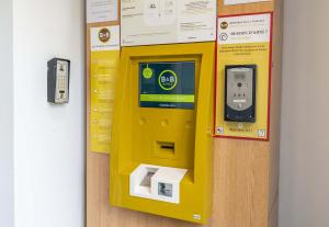 a yellow pay box next to a wall at B&B HOTEL Aix-en-Provence Le Tholonet in Aix-en-Provence
