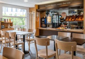 a restaurant with tables and chairs and a counter at B&B HOTEL Aix-en-Provence Le Tholonet in Aix-en-Provence