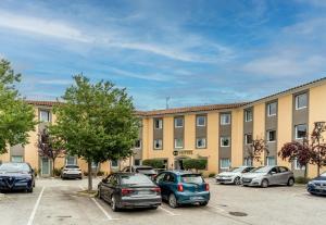 un bâtiment avec des voitures garées dans un parking dans l'établissement B&B HOTEL Aix-en-Provence Le Tholonet, à Aix-en-Provence