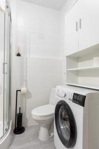 a white bathroom with a washing machine and a toilet at Gliniana 3-Bedroom Apartment in Wrocław
