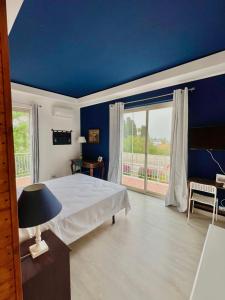 Dormitorio azul con cama y ventana grande en B&B Villa Dunardi, en Fontane Bianche