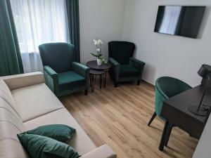 uma sala de estar com um sofá e duas cadeiras e uma mesa em Seehotel Ecktannen em Waren