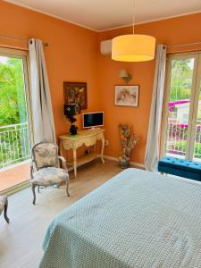1 dormitorio con paredes de color naranja, 1 cama y TV en B&B Villa Dunardi, en Fontane Bianche