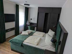 een slaapkamer met een bed met groene en witte kussens bij Seehotel Ecktannen in Waren