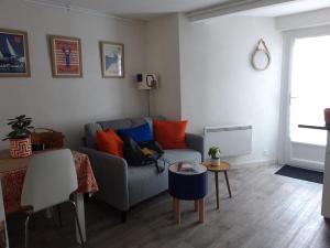 サン・マロにあるBel Appartement St Malo avec jardin à 2 pas de la plage Sillonのリビングルーム(グレーのソファ、オレンジの枕付)