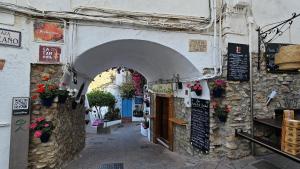 un callejón con un arco en un edificio con flores en Hotel Puntazo II en Mojácar