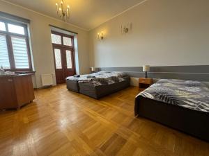 two beds in a large room with wooden floors at Hostel Va Bank in Rzeszów