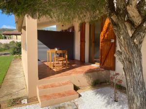 a house with a porch with a table and a tree at La Collina: Il maestrale in Castiadas