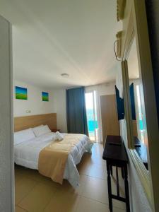 um quarto com uma cama, uma mesa e uma janela em Hostal Mozaik Playa em Lloret de Mar