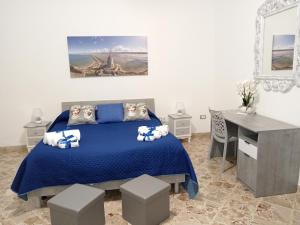 una camera con letto blu e scrivania di Casa Sciacca a Marsala