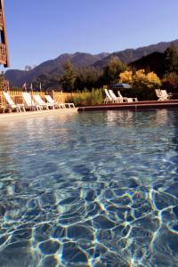 a swimming pool with lounge chairs and a mountain at Residence Hôtelière La Renardiere in Samoëns