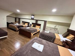 Habitación de hotel con 3 camas y sofá en Hotel Casa Santa Lucía, en Baños