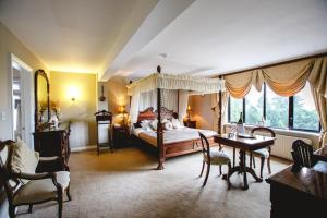AherlowにあるAherlow House Hotel & Lodgesのベッドルーム(天蓋付きベッド1台、テーブル、椅子付)