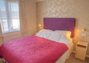 a bedroom with a large bed with a purple headboard at Gwalia Falls in Aberporth