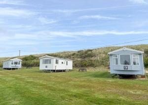 two tiny houses in a field with a picnic table at Anchor Park in Happisburgh