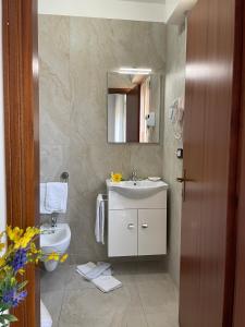 ein Badezimmer mit einem Waschbecken, einem WC und einem Spiegel in der Unterkunft HOTEL LA PLAYA in Cervia