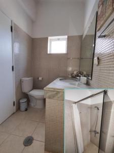 a bathroom with a sink and a toilet and a mirror at Vilas Marrocha in Porches