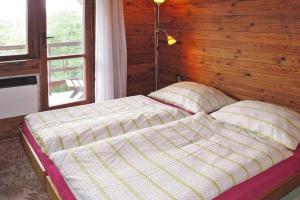 a bed in a room with a wooden wall at Cottage IRENA in Giant Mountains in Černý Dŭl