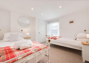 a white bedroom with two beds and a mirror at Silvergate Cottage in West Runton