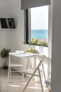 Una mesa blanca y una silla en una habitación con ventana en Relaxing Sea View Studio at Xenios Avlais en Alikanas