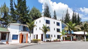 ein weißes Gebäude mit Palmen vor einer Straße in der Unterkunft Hotel Las Palmeras Gachancipa in Gachancipá
