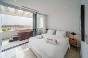 a bedroom with a large white bed and a balcony at Downtown Park in Paphos