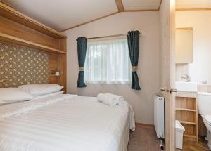 um quarto com uma cama, uma janela e um lavatório em Bucklegrove Holiday Park em Rodney Stoke