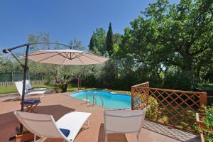 a patio with chairs and an umbrella and a pool at Casale Pontarello - Happy Rentals in Vetralla