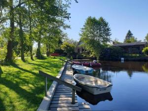 three boats are docked at a dock on a river at Ferienhaus Grosses Meer mit Ruderboot in Südbrookmerland