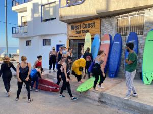 un groupe de personnes debout devant leurs planches de surf dans l'établissement West coast surf house, à Imsouane