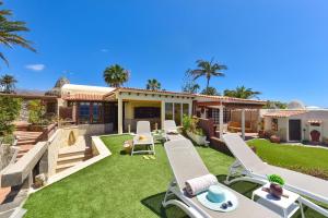 ein Hinterhof mit Gartenstühlen und einem Haus in der Unterkunft Roca del Mar 7 by VillaGranCanaria in Playa del Aguila