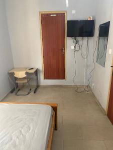 アクラにあるEstepona Playa Hostelのベッド、テレビ、ドアが備わる客室です。