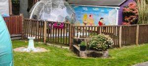 a wooden fence with a yard with a gazebo at The Cabin quiet relaxing and dog friendly in Mauchline