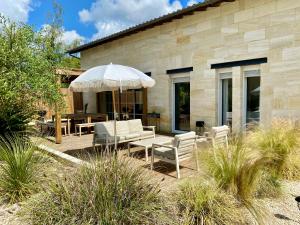 un patio con mesa, sillas y sombrilla en Maison d'exception Girondine en La Lande-de-Fronsac