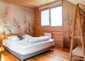 ein Schlafzimmer mit einem Bett in einer Holzhütte in der Unterkunft Le petit Repaire de Sailhan, Ecolodges in Sailhan