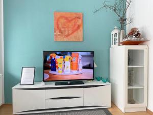 TV en un centro de entretenimiento blanco en una sala de estar en Gemütliches Apartment, Seenähe, WM, WLAN, Balkon en Markkleeberg
