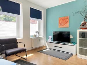 a living room with a television and a chair at Gemütliches Apartment, Seenähe, WM, WLAN, Balkon in Markkleeberg