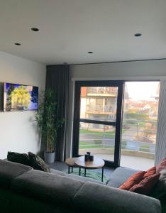 uma sala de estar com um sofá, uma mesa e uma janela em Blutsyde Promenade Cannes Bredene em Bredene