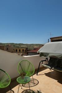 zwei grüne Stühle und ein Regenschirm auf dem Balkon in der Unterkunft La Martina Home in Valguarnera Caropepe