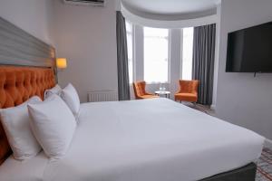 a hotel room with a large white bed and a television at Bournemouth West Cliff Hotel in Bournemouth