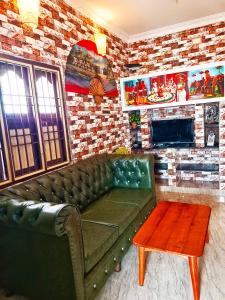 ein Wohnzimmer mit einem grünen Sofa und einer Ziegelwand in der Unterkunft John Beach House in Puducherry