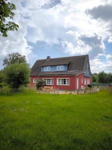 una casa rossa con un prato verde davanti di Ferienhaus am Saaler Bodden a Saal
