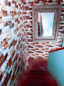 un miroir sur un mur en briques avec un escalier dans l'établissement John Beach House, à Pondichéry