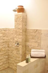 ein Bad mit einer Dusche und einer Steinmauer in der Unterkunft d'Sawah Amed Homestay & Warung in Amed