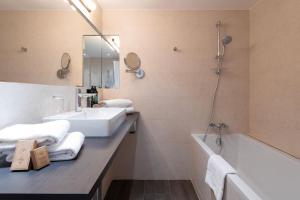 a bathroom with a sink and a bath tub and a mirror at Hôtel Cézanne Boutique-Hôtel in Aix-en-Provence