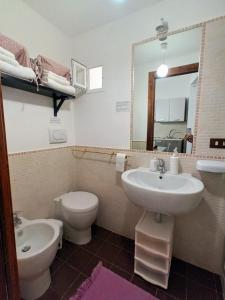 W łazience znajduje się umywalka, toaleta i lustro. w obiekcie Antiche Mura Apartments "Nel Cuore della Puglia"bivani, cucina, terrazzo w mieście Turi