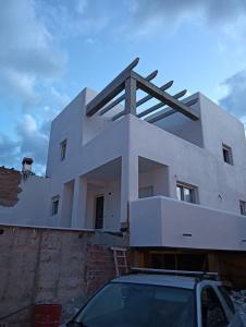 una casa blanca con un coche aparcado delante de ella en Alhamar House with private pool, en Punta Umbría